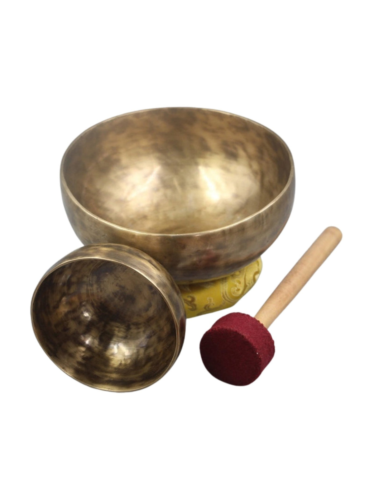 Cuencos tibetanos de latón hechos a mano con cojín amarillo y baqueta de madera con punta roja, en fondo blanco