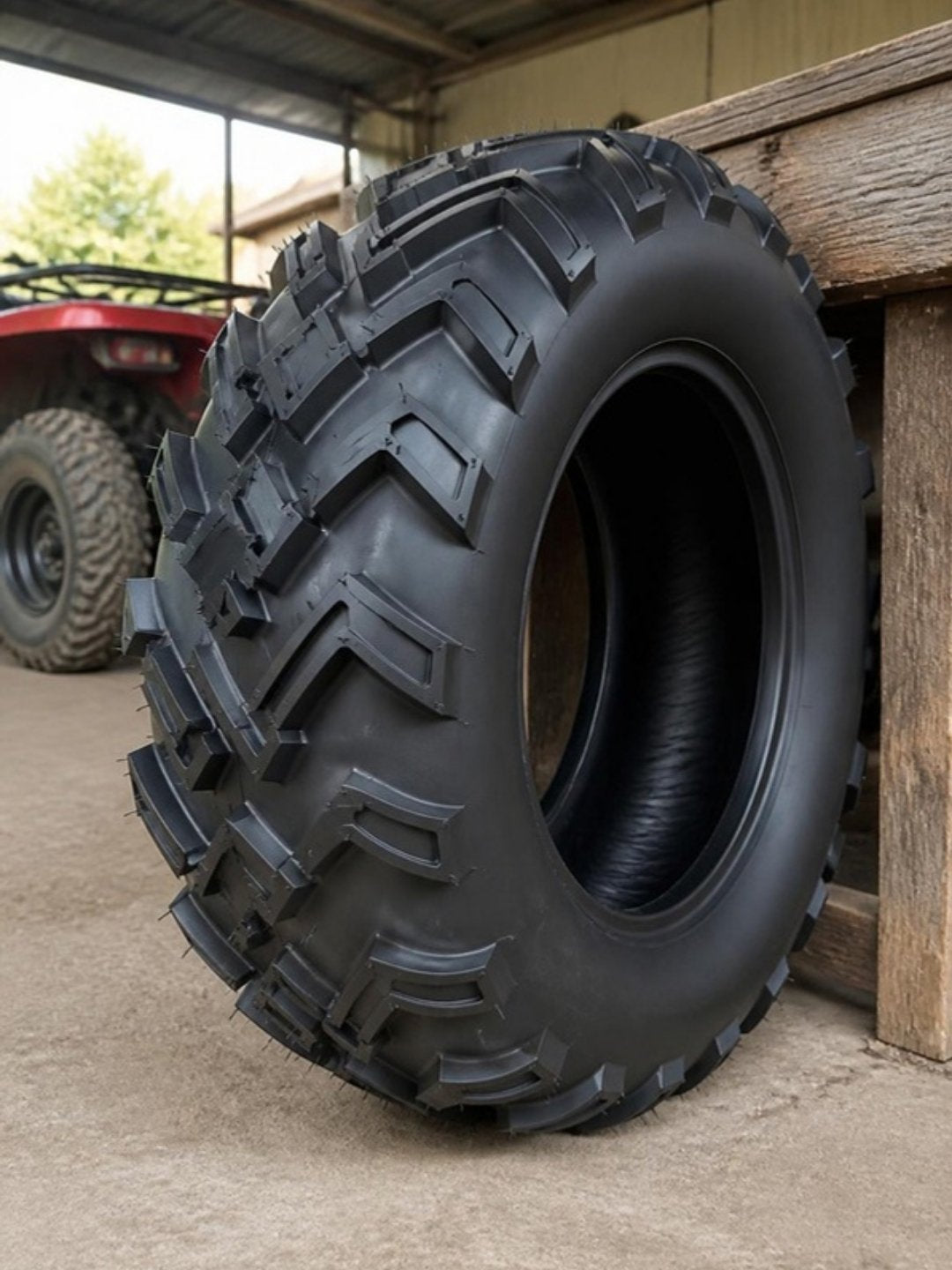 Neumático sin cámara 22x10-10 con taco en chevrón para ATV y go-kart, recargado en un banco de trabajo en un taller techado de rancho