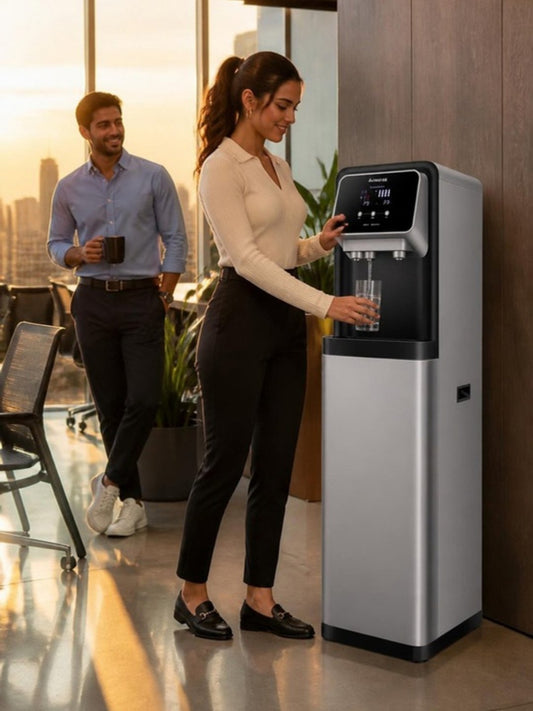 Dispensador de agua fría y caliente en la cocina de una oficina en Ciudad de México, empleada llenando un vaso