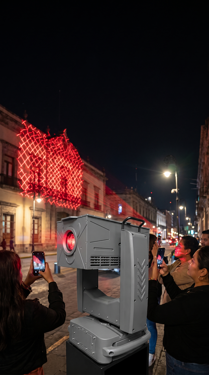 Personas grabando el espectáculo de la luz láser con base robótica en una calle de noche
